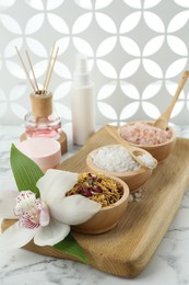 Beautiful composition with different spa products and orchid on white marble table