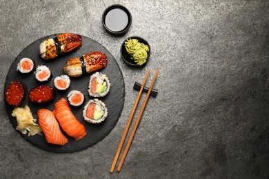 Photo of Set of delicious sushi rolls on dark grey table, flat lay