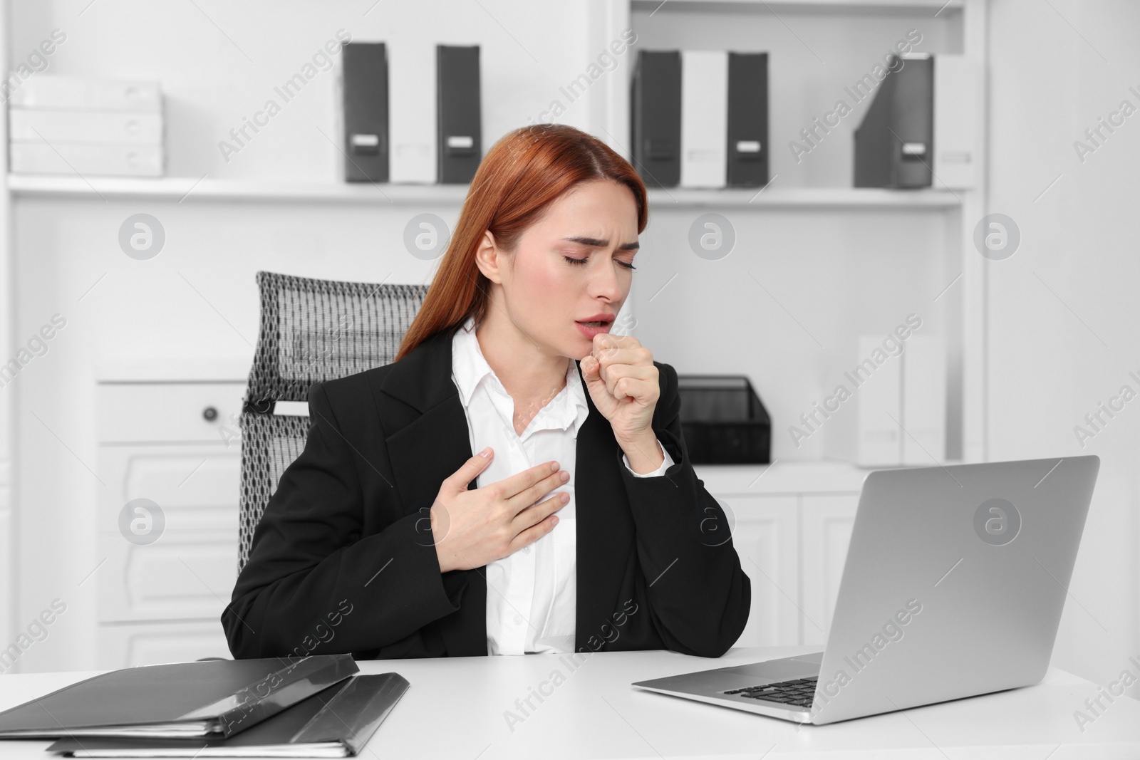 Photo of Woman coughing at table in office. Cold symptoms