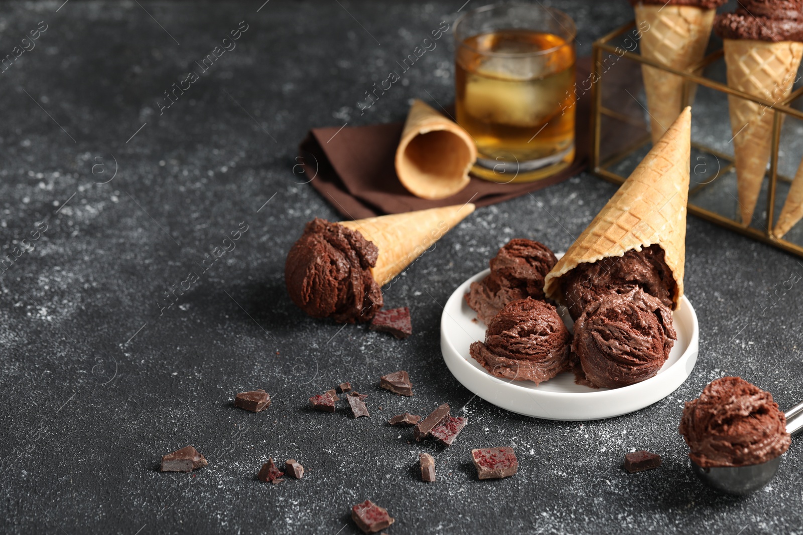 Photo of Tasty ice cream scoops, chocolate crumbs and waffle cones on dark textured table. Space for text