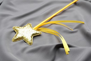 Photo of Beautiful golden magic wand on grey fabric