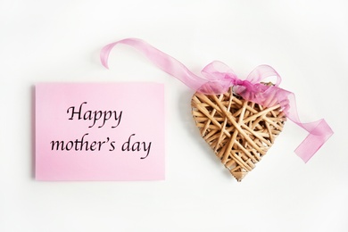 Photo of Card with words "Happy Mother's day" and wicker heart figure on light background, top view