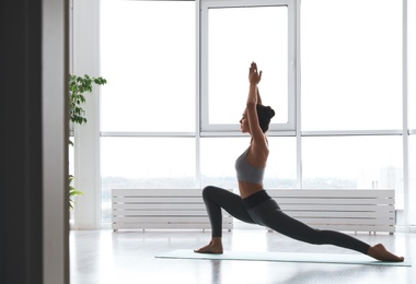 Young woman practicing crescent pose in yoga studio