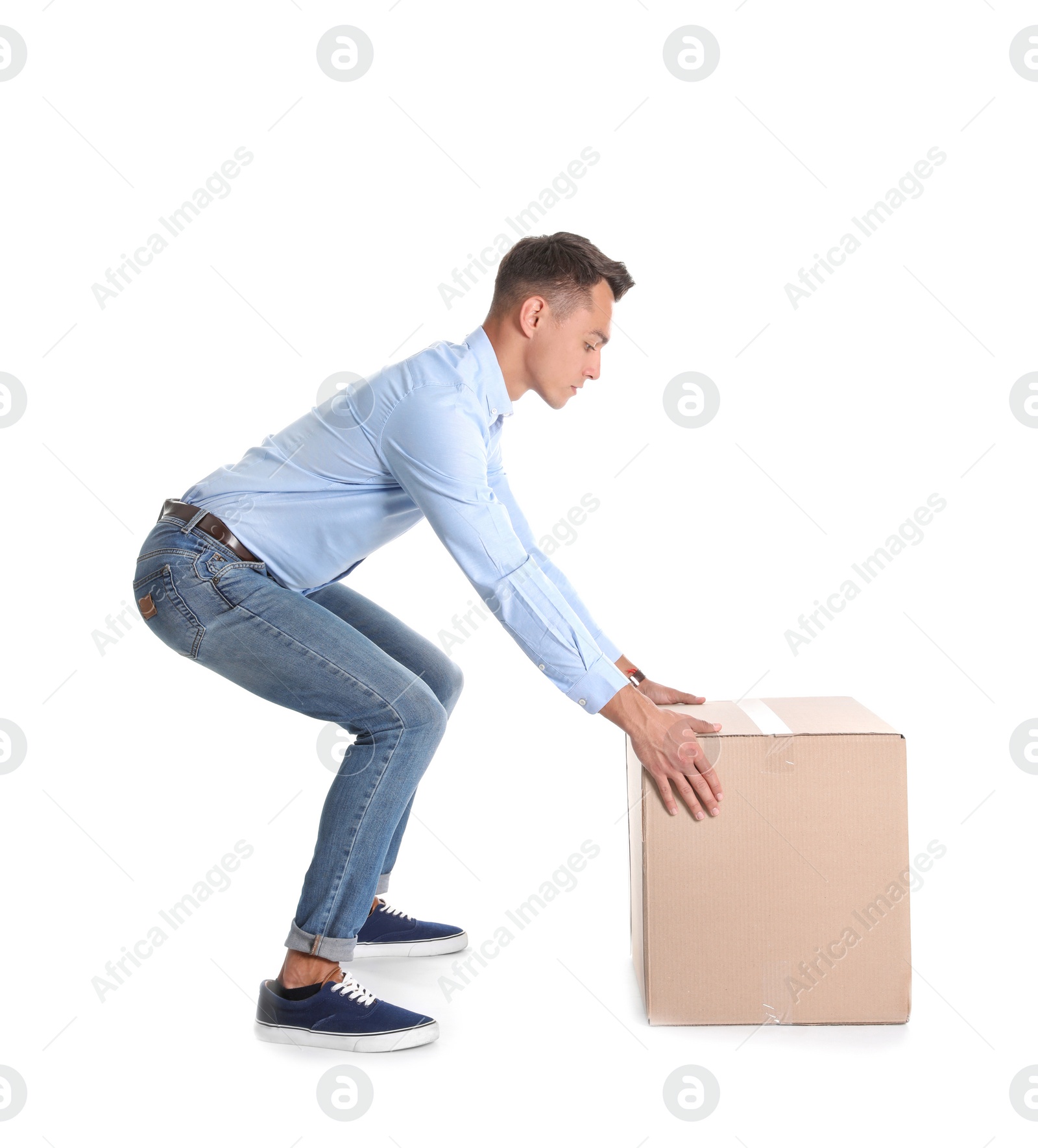 Photo of Full length portrait of young man lifting heavy cardboard box on white background. Posture concept