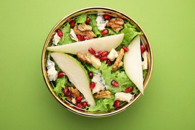 Photo of Delicious pear salad in bowl on green background, top view