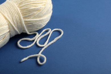 Soft white woolen yarn on blue background, closeup