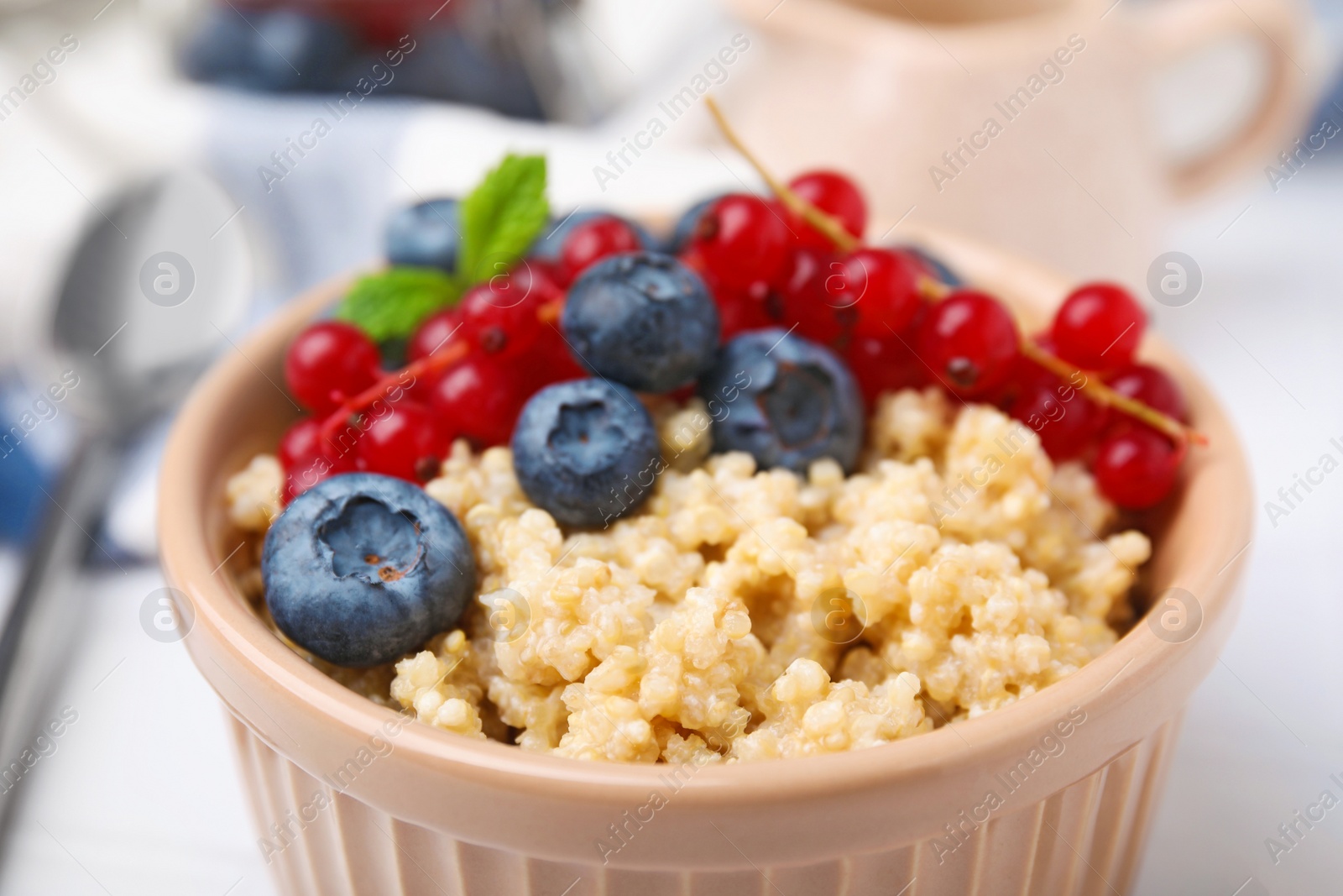 Photo of Bowl of delicious cooked quinoa with blueberries and cranberries , closeup