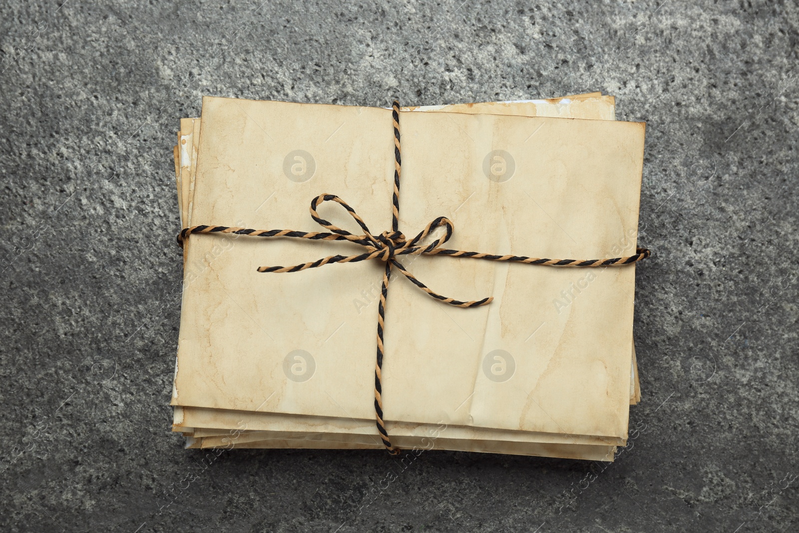 Photo of Stack of old letters tied with string on grey table, top view