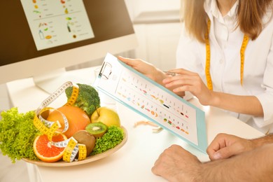 Image of Young nutritionist consulting patient at table in clinic, closeup