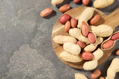 Photo of Fresh unpeeled peanuts on grey table, top view. Space for text