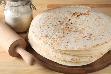 Photo of Many tasty homemade tortillas on wooden table, closeup