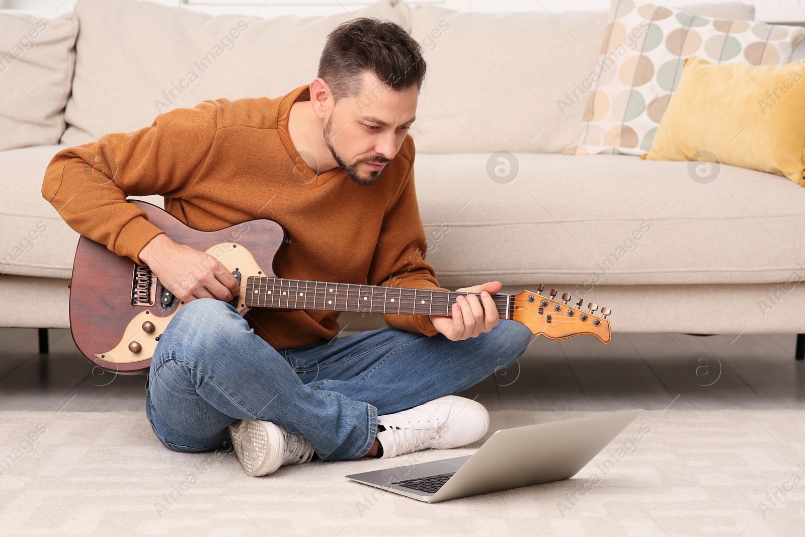 Photo of Man learning to play guitar with online music course at home. Time for hobby