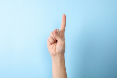 Photo of Woman showing number one on color background, closeup. Sign language