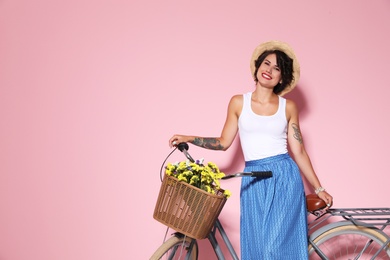 Portrait of beautiful young woman with bicycle on color background