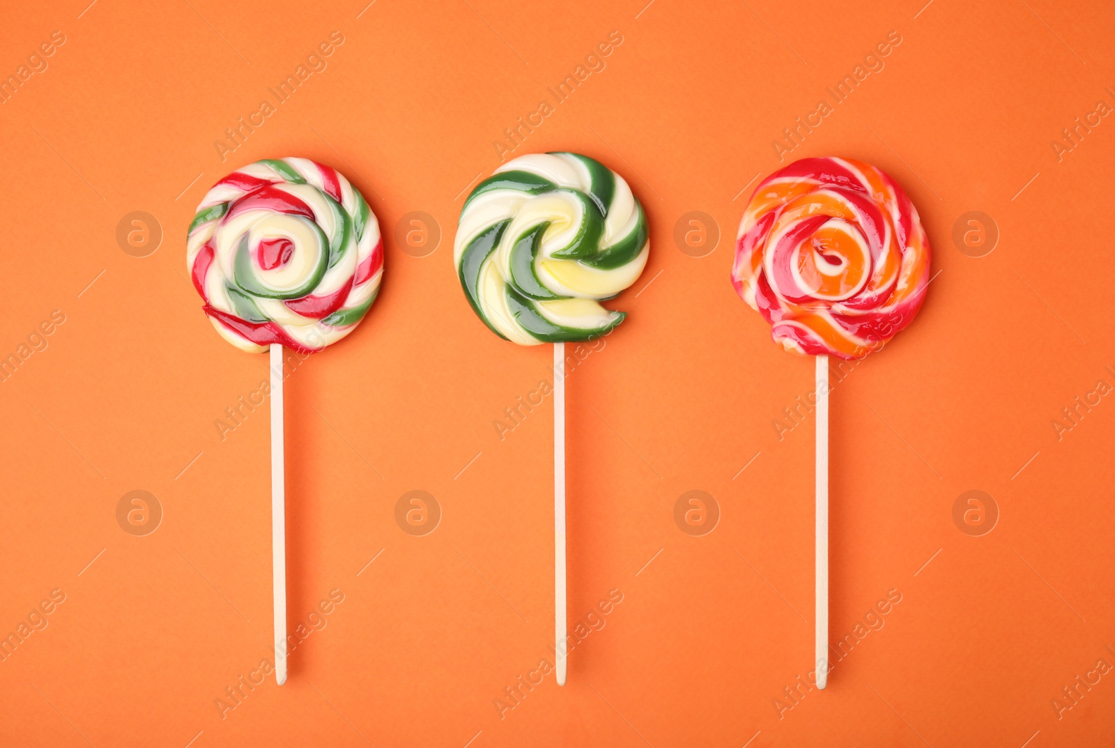 Photo of Colorful lollipops on orange background, flat lay