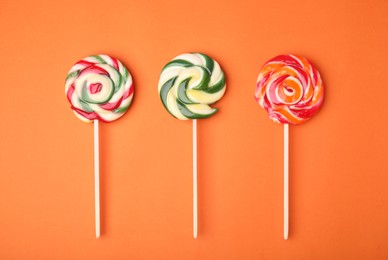 Photo of Colorful lollipops on orange background, flat lay