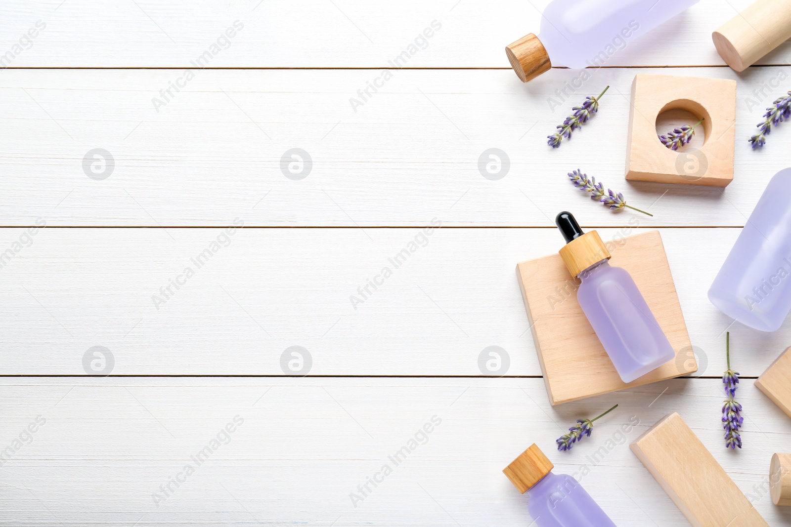 Photo of Flat lay composition with bottles of essential oil and flowers on white wooden table. Space for text