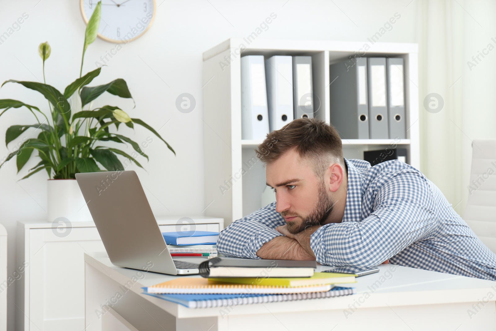 Photo of Lazy young man wasting time at table in office