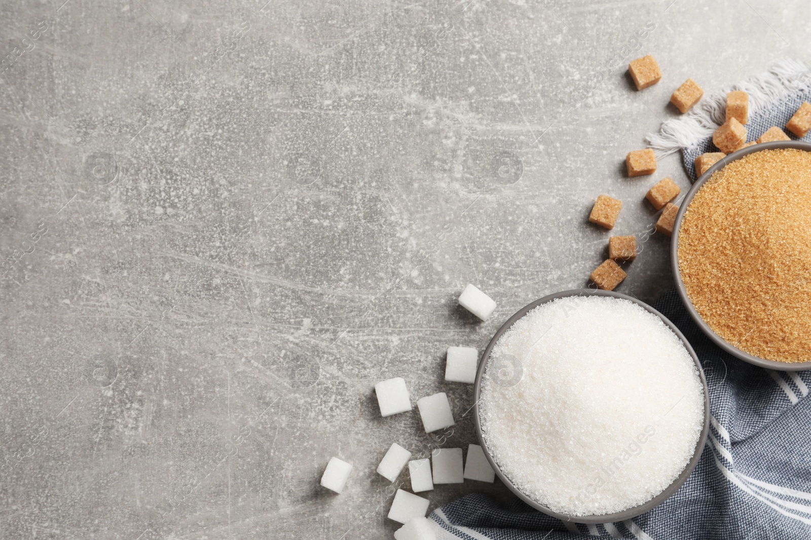 Photo of White and brown sugar on light grey table, flat lay. Space for text