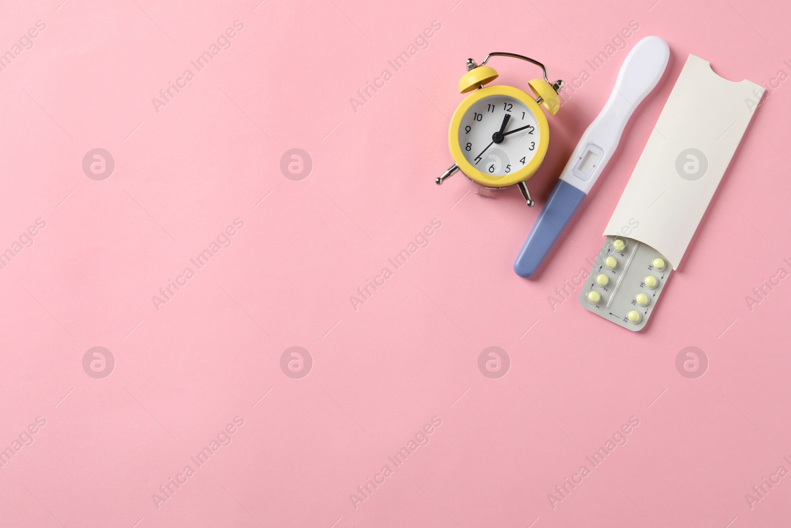 Photo of Oral contraceptive pills, pregnancy test and alarm clock on pink background, flat lay. Space for text