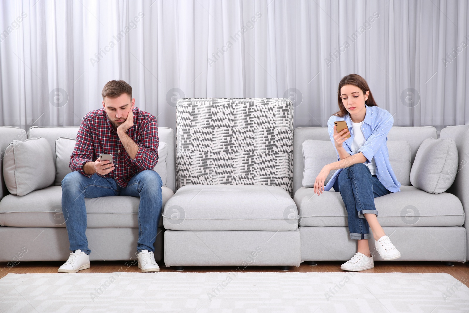 Photo of Couple addicted to smartphones ignoring each other at home. Relationship problems