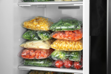 Plastic bags with different frozen vegetables in refrigerator