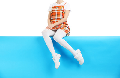 Woman wearing white tights and stylish shoes sitting on color background, closeup