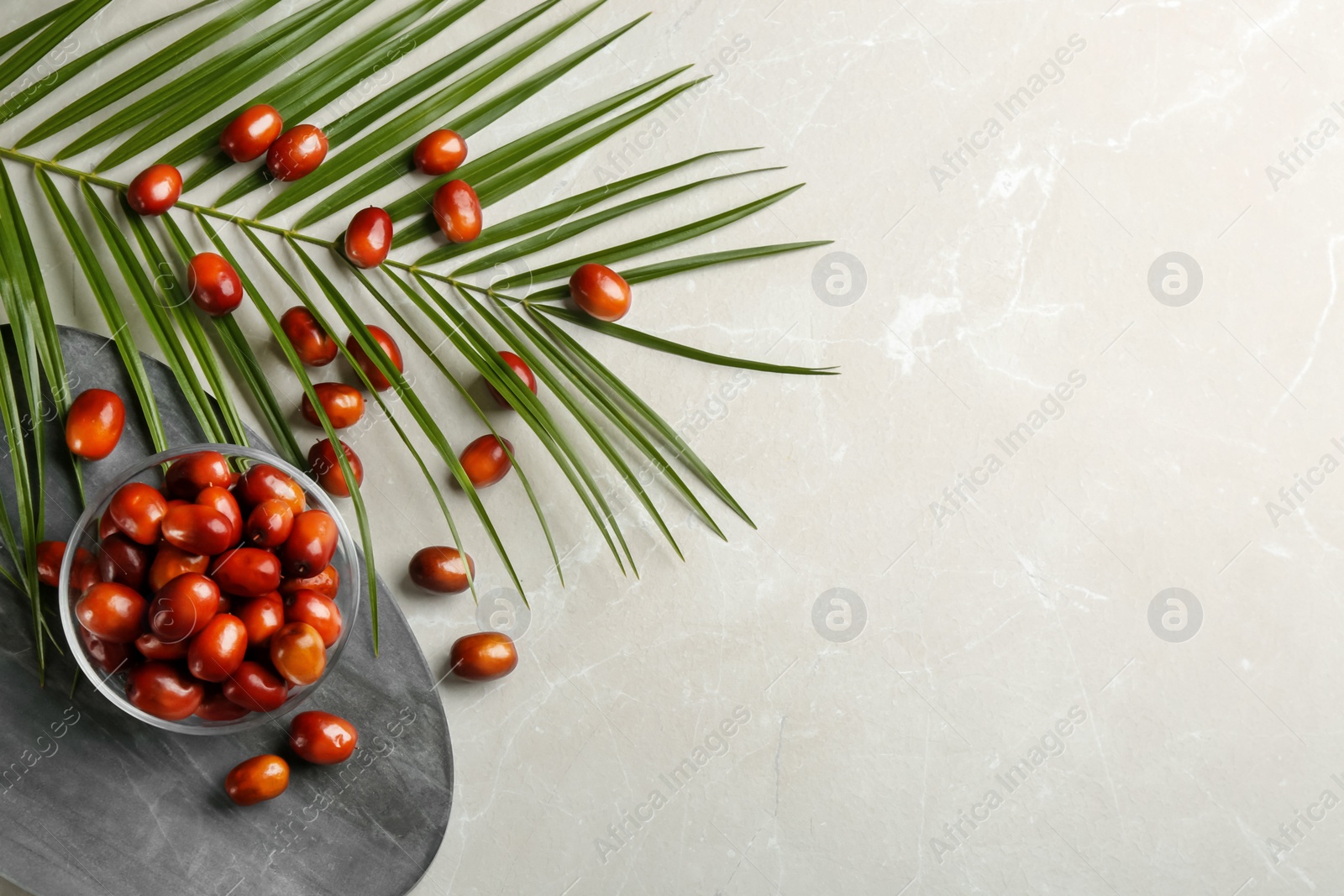 Photo of Palm oil fruits in bowl on light marble table, flat lay. Space for text