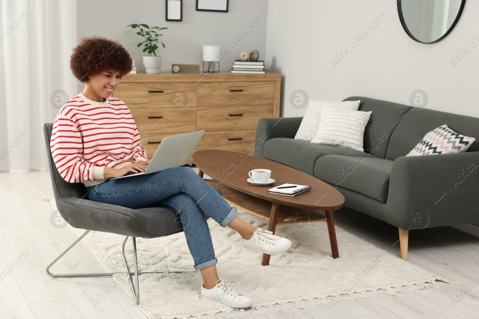 Photo of Beautiful young woman using laptop in room, space for text