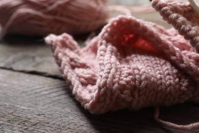Photo of Pink knitting on wooden table, closeup. Space for text