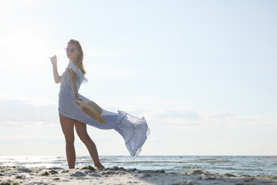 Photo of Woman in dress with straw hat walking by sea on sunny day