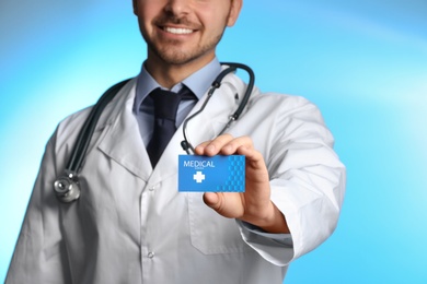 Photo of Doctor holding business card on color background, closeup. Medical service