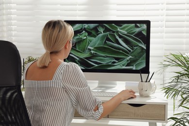 Woman working on computer at table in room, back view. Interior design