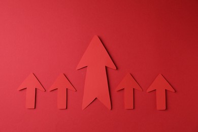 Photo of Many paper arrows on red background, flat lay