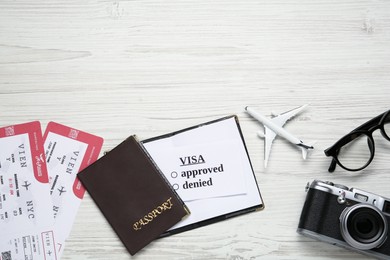 Flat lay composition with passport, toy plane and tickets on white wooden background, space for text. Visa receiving