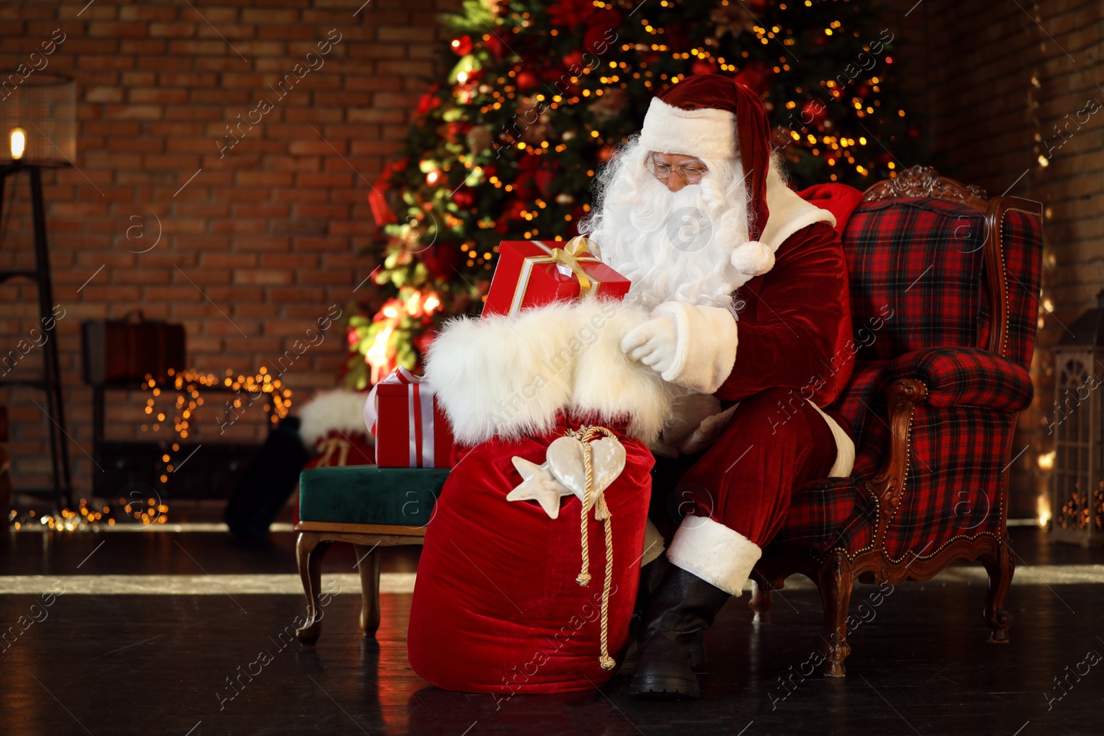 Photo of Santa Claus with gift sack near Christmas tree indoors