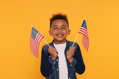 Photo of 4th of July - Independence Day of USA. Happy boy with American flags on yellow background