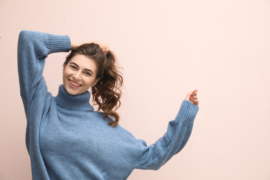Photo of Beautiful young woman wearing warm blue sweater on light pink background
