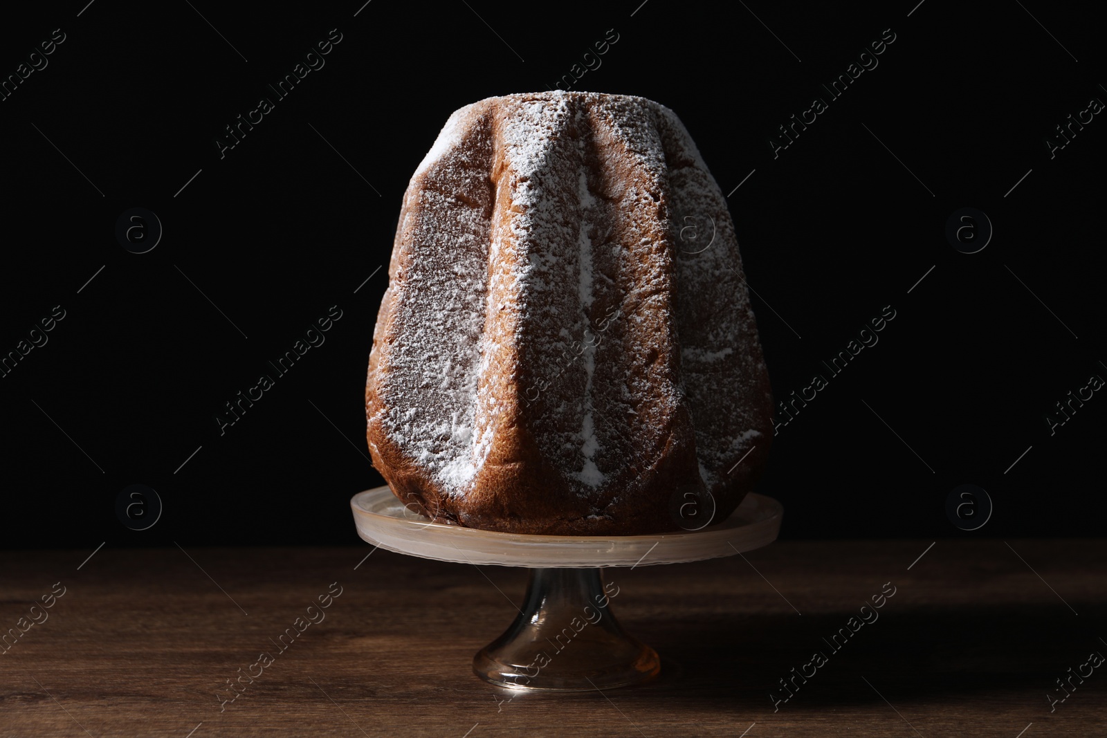 Photo of Delicious Pandoro cake decorated with powdered sugar on wooden table. Traditional Italian pastry