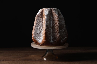 Delicious Pandoro cake decorated with powdered sugar on wooden table. Traditional Italian pastry