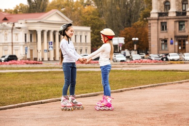 Photo of Happy children wearing roller skates on city street