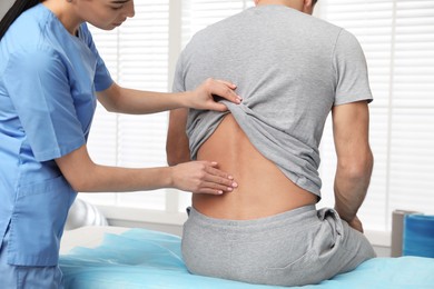 Photo of Orthopedist examining man's back in clinic. Scoliosis treatment
