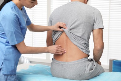 Orthopedist examining man's back in clinic. Scoliosis treatment