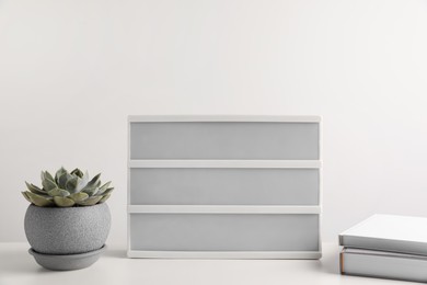 Photo of Blank letter board, books and beautiful houseplant on white table. Mockup for design