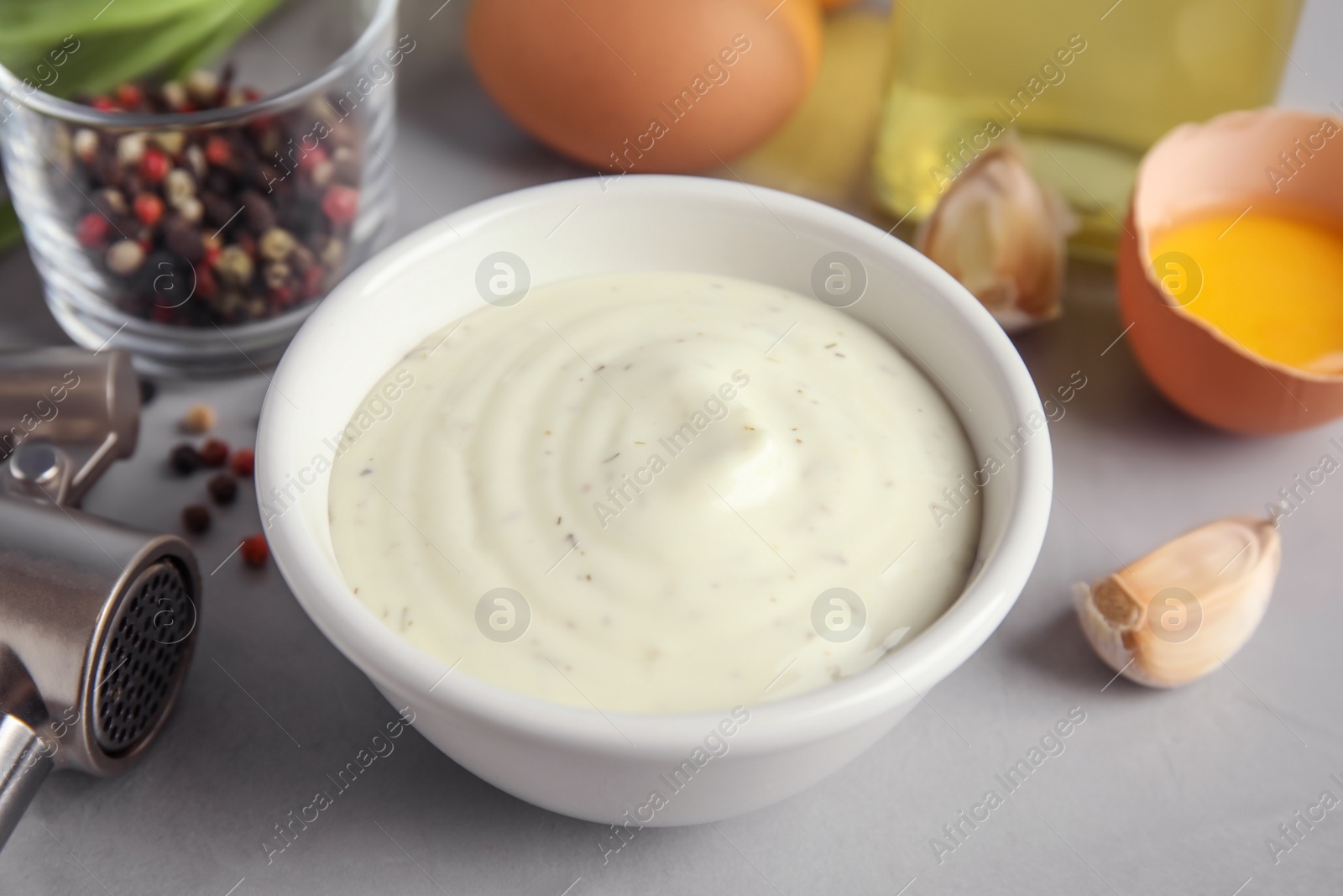 Photo of Composition with bowl of garlic sauce on grey table