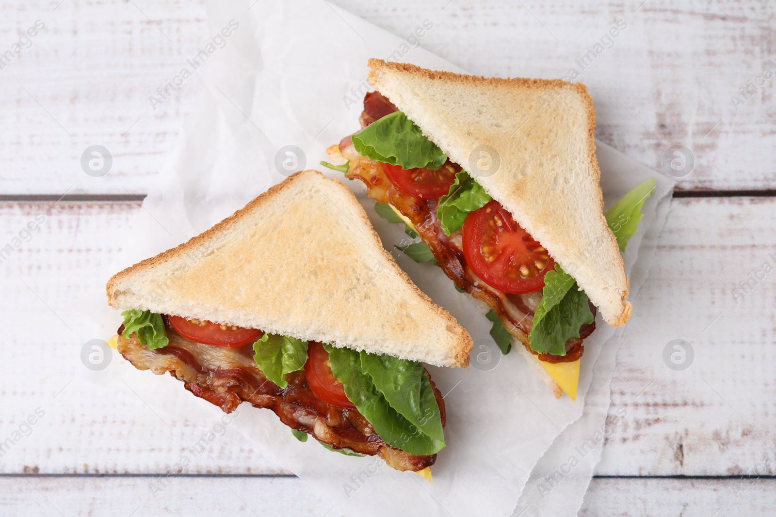 Photo of Delicious sandwiches with fried bacon on wooden rustic table, top view