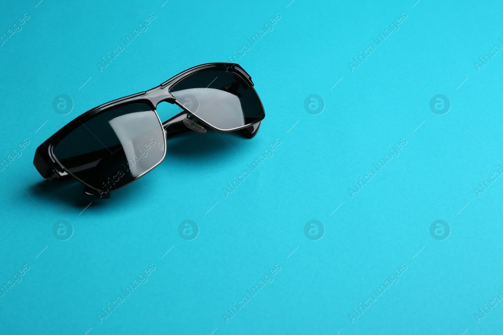 Photo of Stylish sunglasses on blue background, space for text. Fashionable accessory