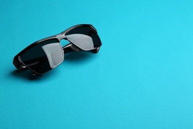 Photo of Stylish sunglasses on blue background, space for text. Fashionable accessory