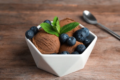Photo of Bowl of chocolate ice cream and blueberries on wooden table