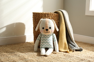 Photo of Cute toy dog and basket with plaid indoors. Baby room interior elements